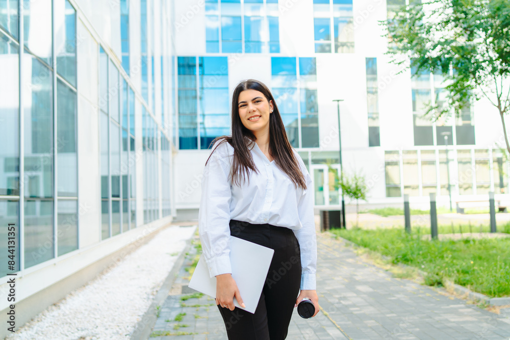 Fototapeta premium One young successful business woman going to work at business office modern building while holding coffee and papers 