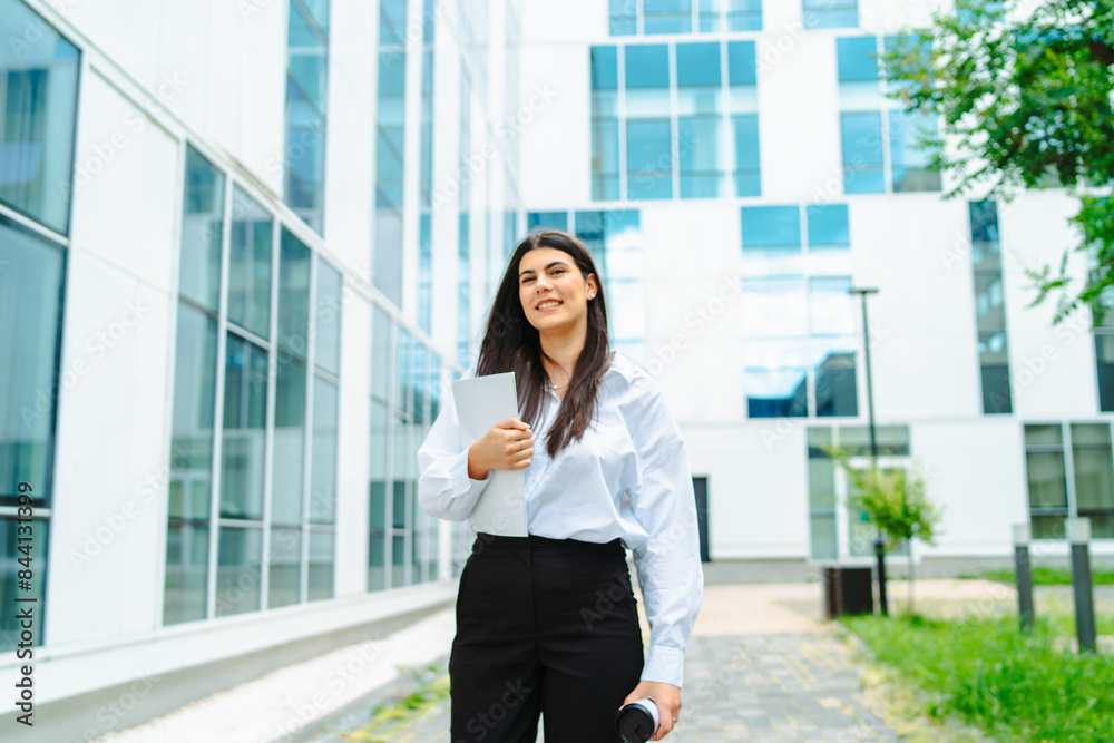 One young successful business woman going to work at business office modern building while holding coffee and papers One young successful business woman going to work at business office modern building while holding coffee and papers