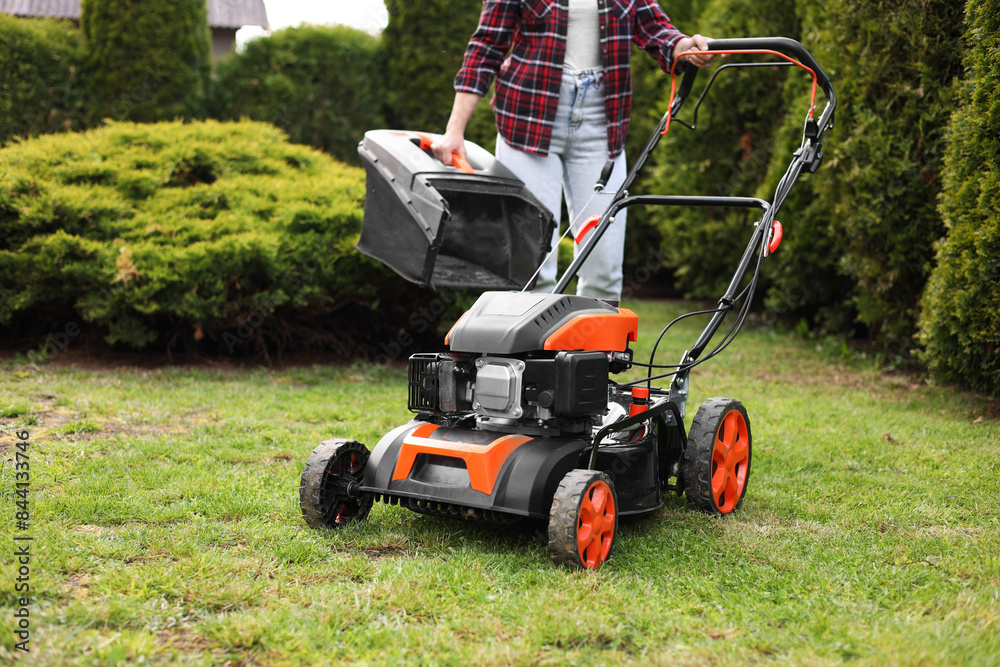 Obraz premium Woman with modern lawn mower in garden, closeup