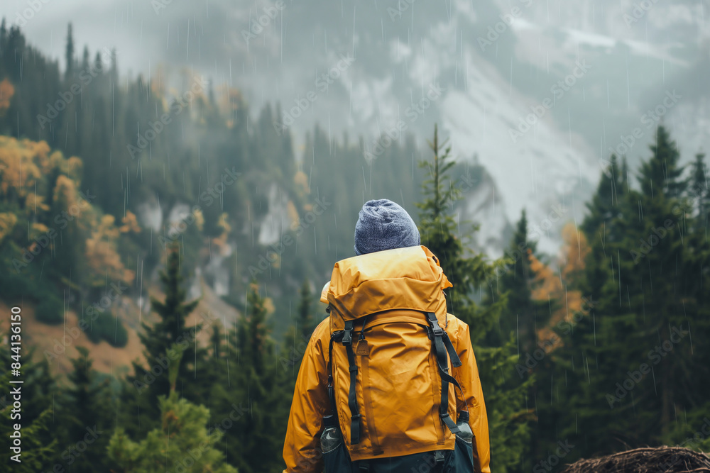 Man with a backpack standing in the rain in the mountains Man with a backpack standing in the rain in the mountains