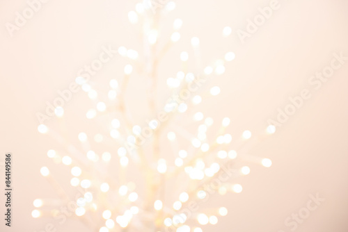Decorative tree with lights on beige background, blurred view