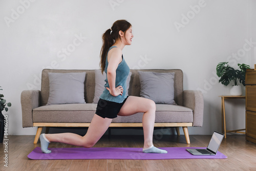 Woman stretching on purple mat in living room.