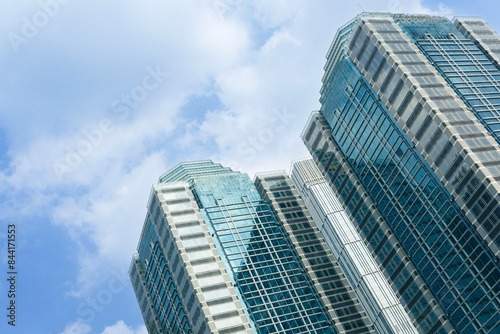Modern office buildings exterior towering against blue sky. Jakarta Indonesia skyline viewed from below with facade of apartments  condominiums and offices.