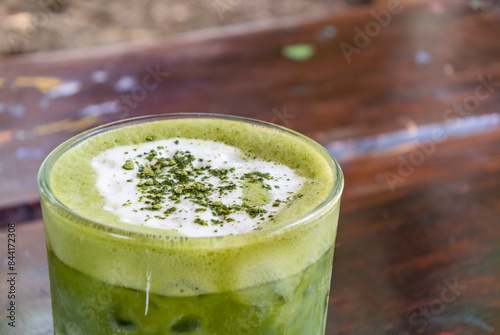 Matcha latte green milk foam cup on wood table