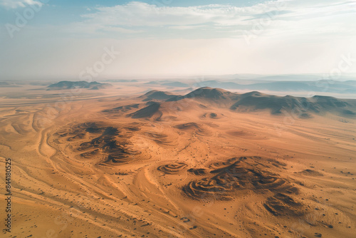 Aerial view of a desert landscape from a drone perspective  featuring rolling sand dunes and distant mountains  perfect for a nature-inspired wallpaper