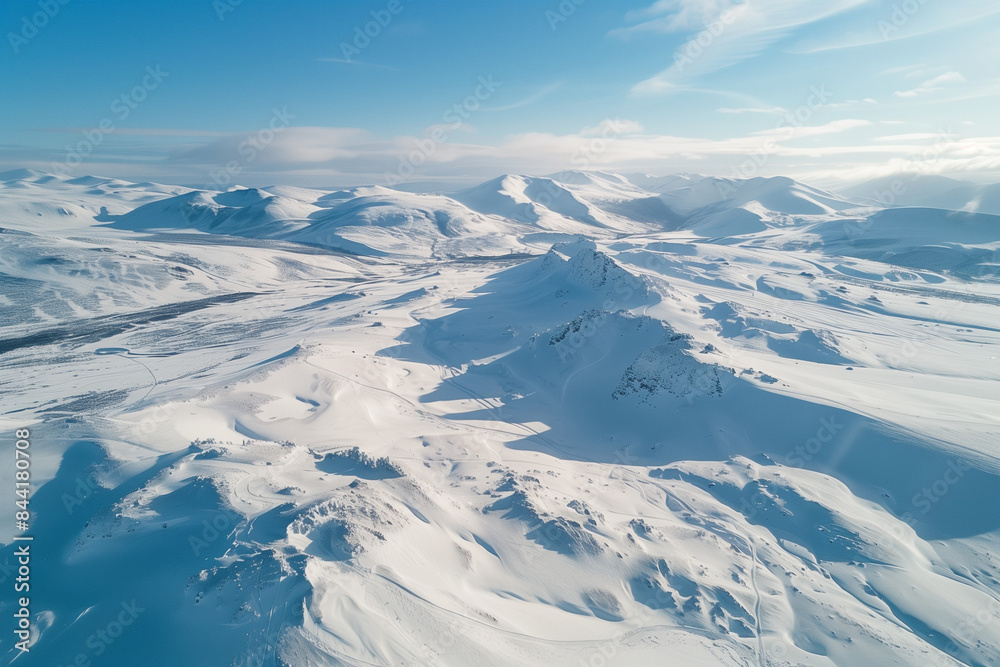 Aerial view of a snowy mountain landscape provided by a drone, highlighting the contrast between the pristine snow and rugged peaks, ideal for a wallpaper