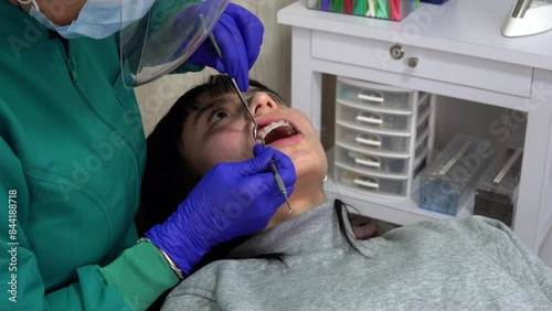 A woman with braces is getting her teeth cleaned by a dentist