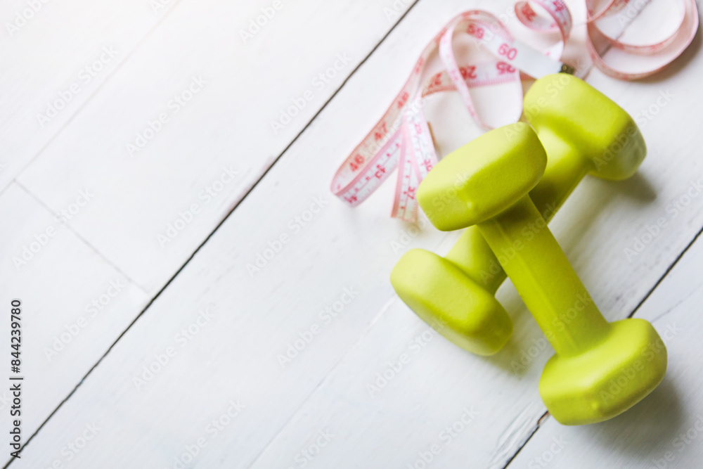 Tape measure, dumbbells and lose weight with fitness for health, workout goals and strong body. Weights, check progress and results for muscle growth on wood table with exercise and training wellness Tape measure, dumbbells and lose weight with fitness for health, workout goals and strong body. Weights, check progress and results for muscle growth on wood table with exercise and training wellness