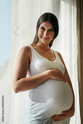 Pregnant, portrait and woman by window in home hold stomach for love, prenatal care and support in morning. Family, pregnancy and person hug tummy for wellness, baby health and maternity in house