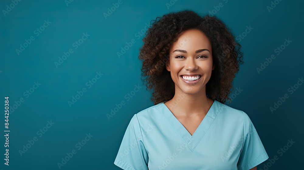 Photograph of a smiling female doctor looking at the camera with a warm and friendly expression, her face taking up most of the frame. The background is a clear blue wall. Photograph of a smiling female doctor looking at the camera with a warm and friendly expression, her face taking up most of the frame. The background is a clear blue wall.