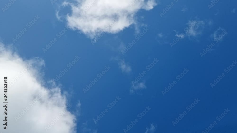 snowy white clouds moving fast and dissolving in blue clear sky