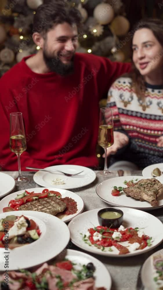 Couple having Christmas dinner, surrounded by decorations, sipping champagne in cozy and romantic setting Couple having Christmas dinner, surrounded by decorations, sipping champagne in cozy and romantic setting