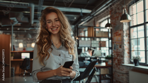 Happy young businesswoman using mobile phone in office