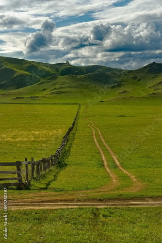 Russia. The South of Western Siberia, the Altai Mountains. A wooden fence stretching into the distance in the mountain steppes along the road along the Uymon valley. photo