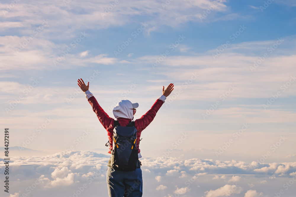 Woman standing over the clouds with her hands raised Woman standing over the clouds with her hands raised