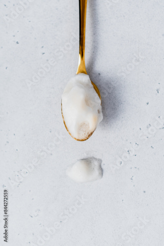 Close-up of a golden tea spoon filled with milk foam photo