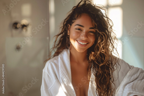 a woman in a bathrobe smiles while standing in a bathroom photo