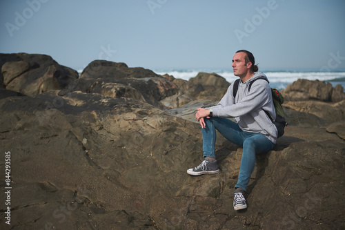 Man sitting on rocks at the beach  enjoying the ocean view and peaceful moment