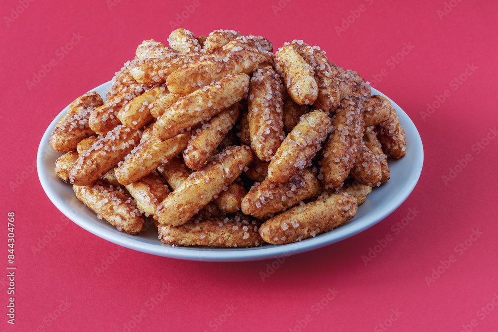 A large pile of sugar and cinnamon cookies on a plate A large pile of sugar and cinnamon cookies on a plate