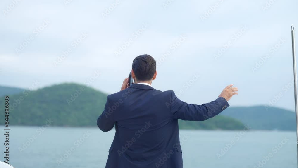 4K Caucasian businessman executive speaking on mobile phone for remote working corporate business during travel on luxury private catamaran boat yacht sailing in the ocean on summer holiday vacation. 4K Caucasian businessman executive speaking on mobile phone for remote working corporate business during travel on luxury private catamaran boat yacht sailing in the ocean on summer holiday vacation.