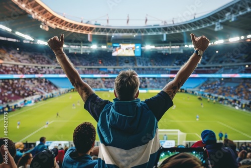 Back view of a man with arms raised cheering at a soccer game in the stadium © ChaoticMind