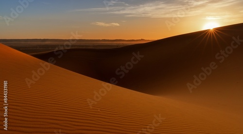 view of the sand dunes at Erg Chebbi in Morocco at sunset with a sunstar