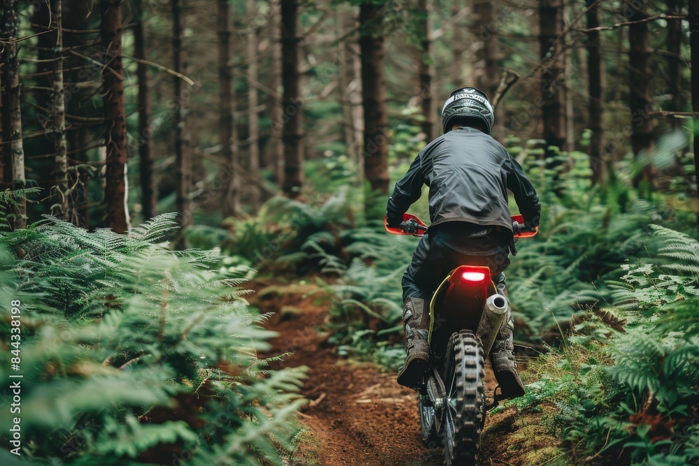 A rider navigating through a forest trail on a motocross bike A rider navigating through a forest trail on a motocross bike