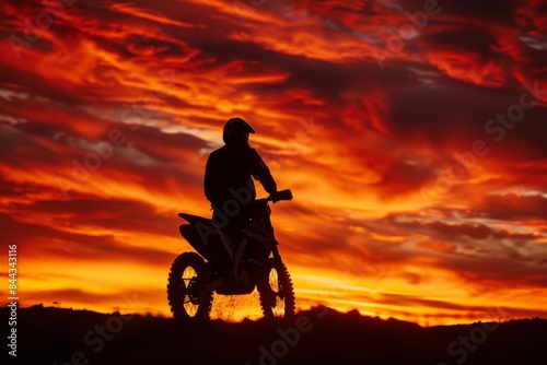 A motocross rider's silhouette against a fiery sunset sky photo