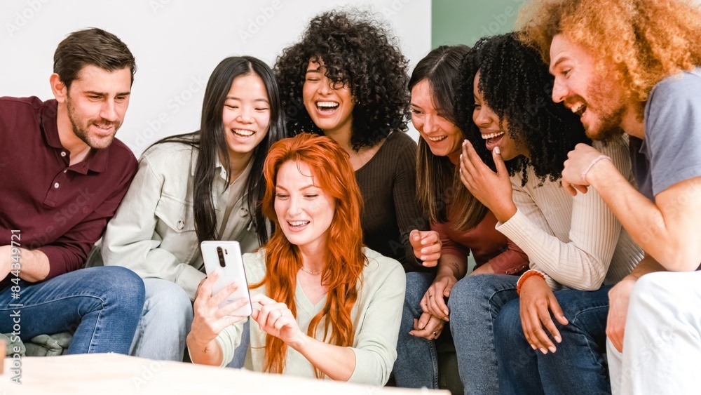 Happy woman showing smartphone to cheerful diverse friends in living room at home Happy woman showing smartphone to cheerful diverse friends in living room at home