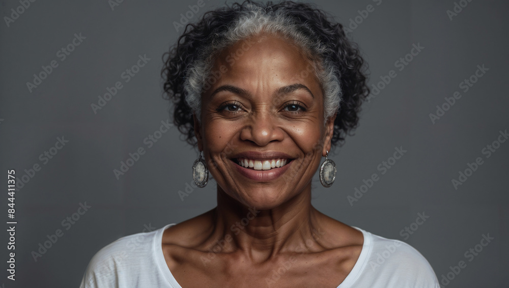 Donna di mezza età di origini africane posa sorridente in uno studio fotografico con sfondo grigio Donna di mezza età di origini africane posa sorridente in uno studio fotografico con sfondo grigio