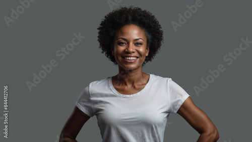 Giovane donna di origini africane posa sorridente in uno studio fotografico con sfondo grigio photo