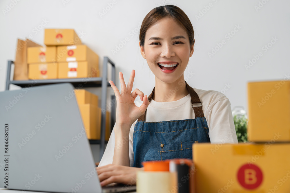 Owner holding packing carton parcel box with shows ok sign, working at the home office, seller prepares the delivery. Startup small business. Owner holding packing carton parcel box with shows ok sign, working at the home office, seller prepares the delivery. Startup small business.