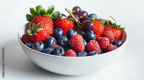 A bowl of vibrant fruits  including strawberries  blueberries  and grapes  sits against a white backdrop.