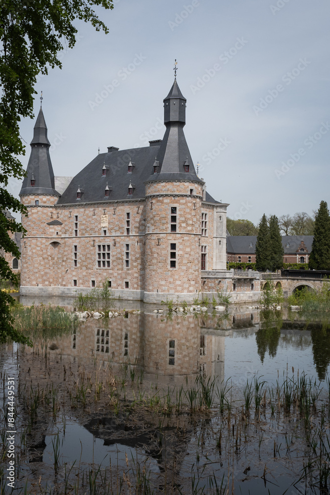 Naklejka premium Jehay Bodegnée Castle Château in Belgium Ardennes. historic fortified building popular tourist attraction on sunny summer day. fresh water moat surrounds rural landmark structure near Liège