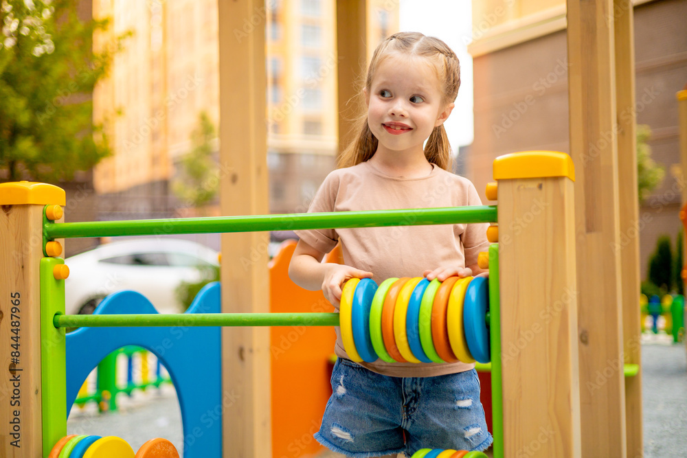 a child girl on the playground in the courtyard of a multi-storey house in the summer has fun playing and fooling around, summer holidays a child girl on the playground in the courtyard of a multi-storey house in the summer has fun playing and fooling around, summer holidays
