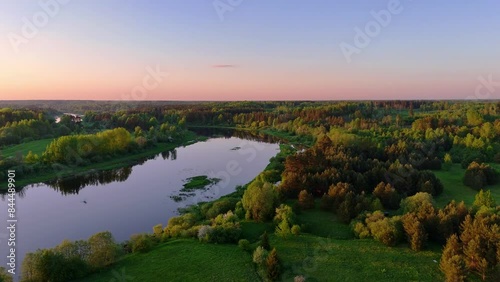 A beautiful evening with a rosy sunset over the forest and river in summer. drone view