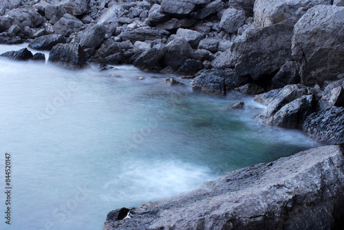 Carta da parati long exposure seashore using tripod motion water above stones lowtide