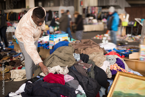 South African guy selects second-hand clothes at a flea market