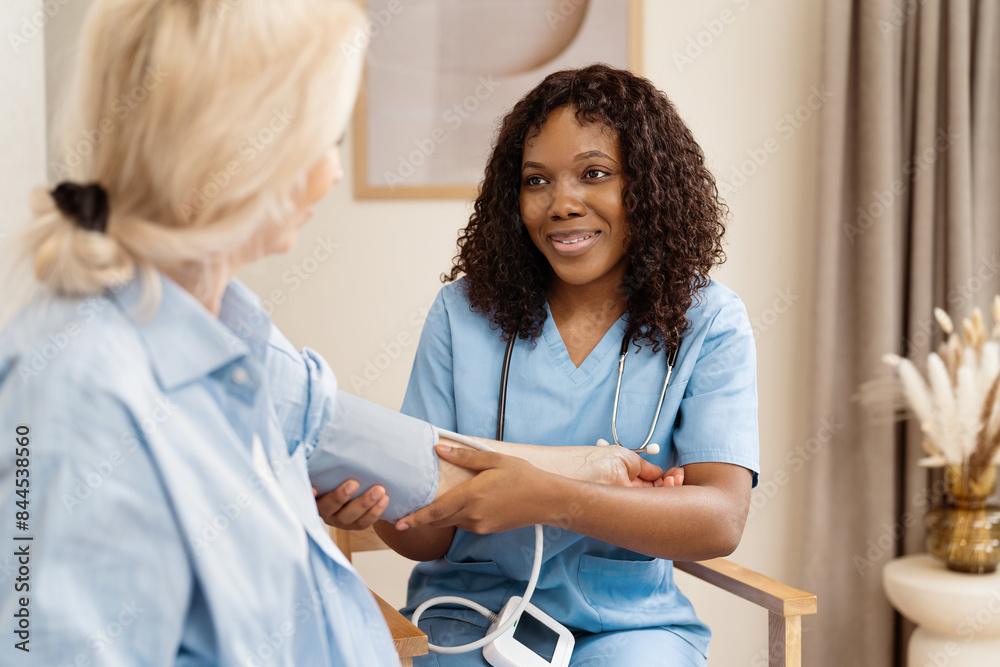 Obraz premium Nurse Checking Blood Pressure Of Senior Woman In Home Care Setting, Emphasizing Compassion, Health, And Senior Living