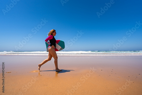 Photos Beautiful woman holding bodyboard  running on sunny beach Bordeira praia, Algarv