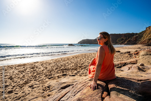 Beautiful woman sitting on sunny beach Portugal, Algarve, Amado praia