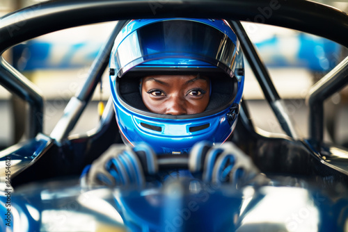 Black Female race car driver in a blue helmet, intensely focused at the start line, embodying concentration and determination