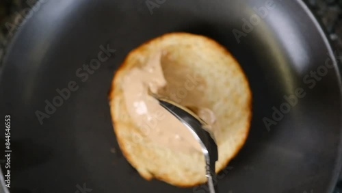 Chef putting sauce on a hamburger bun in black gloves slow motion