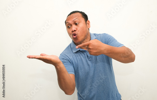 Attractive Asian man smiling while pointing to his open hand palm photo
