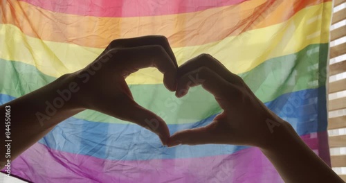 Gay and lesbian pride lgbt flag. LGBT rights. human relationships. Supporting hands make heart sign and wave in front of a rainbow flag flying. Love sign. Celebration Event Symbol Of LGBT. Love Equal. photo