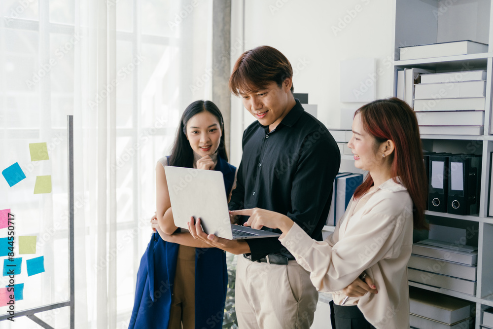 © Parichat - Young Professionals Collaborating in Modern Office with Laptop and Sticky Notes on Glass Wall, Smiling and Discussing Ideas, Bright and Airy Workspace, Teamwork and Innovation Concept
