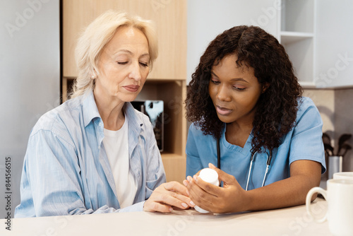 Nurse Assisting Senior Woman With Medication In Home Environment