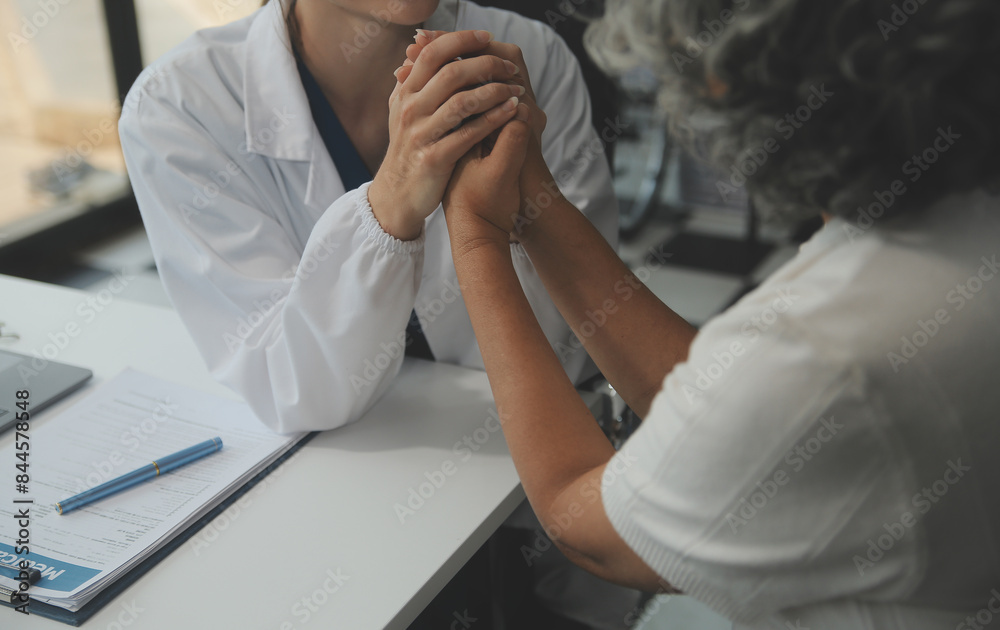 Obraz premium African female doctor hold hand of caucasian woman patient give comfort, express health care sympathy, medical help trust support encourage reassure infertile patient at medical visit, closeup view.