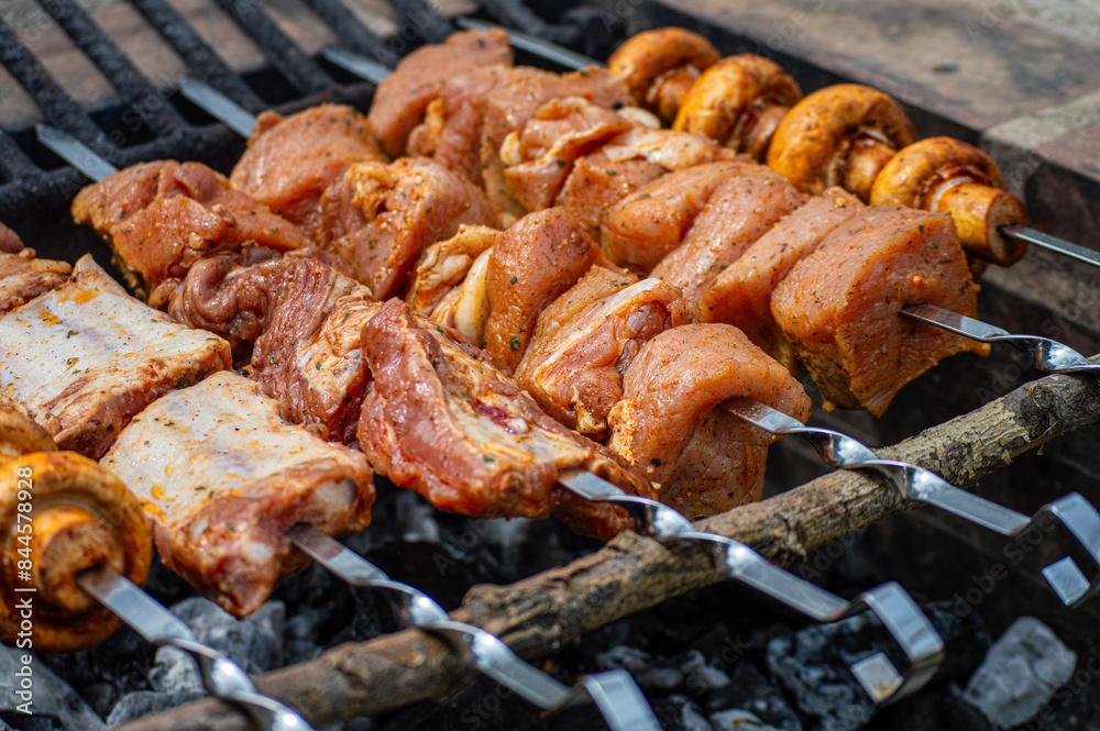 Grilled pieces of pork meat and mushrooms on metal skewers. Shashlik or shish kebab prepared on barbecue grill over hot charcoal with grilled vegetables. Grilled pieces of pork meat and mushrooms on metal skewers. Shashlik or shish kebab prepared on barbecue grill over hot charcoal with grilled vegetables.