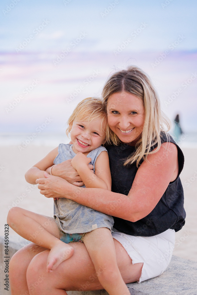 Mother and child embracing on the beach with pink and purple sunset sky Mother and child embracing on the beach with pink and purple sunset sky
